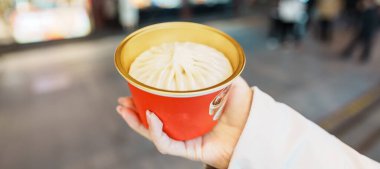 woman traveler visiting in Shanghai, China. Happy Female Tourist eating Xiaolongbao in Yuyuan Old Street market at night. landmark and popular for tourism attractions. Travel and Vacation  clipart