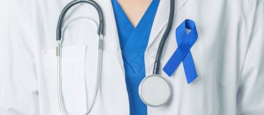 March Colectal Kanser Farkındalığı Ayı. Koyu mavi kurdeleli bir doktor. Yaşayan ve hastalıklı insanları destekliyor. Sağlık, umut ve Dünya Kanser Günü konsepti