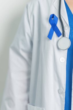 March Colectal Kanser Farkındalığı Ayı. Koyu mavi kurdeleli bir doktor. Yaşayan ve hastalıklı insanları destekliyor. Sağlık, umut ve Dünya Kanser Günü konsepti