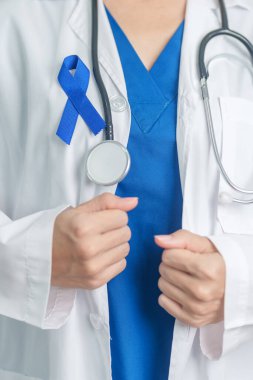 March Colectal Kanser Farkındalığı Ayı. Koyu mavi kurdeleli bir doktor. Yaşayan ve hastalıklı insanları destekliyor. Sağlık, umut ve Dünya Kanser Günü konsepti