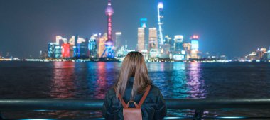 Çin, Şangay 'ı ziyaret eden bir kadın gezgin. Sırt çantalı bir bayan turist Şangay 'da Lujiazui' nin Şangay 'daki Bund of Shanghai manzarasını seyrediyor. tarihi eser ve turizm turizmi için popüler.
