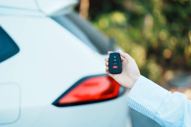 El ele tutuşan uzaktan kumanda, beyaz arabanın arka kapısını kilitlemek ya da açmak için akıllı anahtar. Güvenlik, seyahat ve ulaşım kavramı