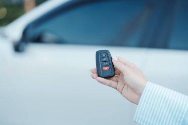 El ele tutuşan araba uzaktan kumandası, beyaz arabanın kapılarını kilitlemek ya da açmak için akıllı anahtar. Güvenlik, seyahat ve ulaşım kavramı