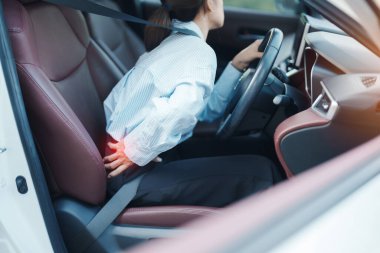 Uzun süre araba kullanırken sırtı burkulmuş bir kadın. Piriforis Sendromu, bel ağrısı ve omurga sıkışması nedeniyle sırt ağrısı çekiyor. Ergonomik ve tıbbi konsept