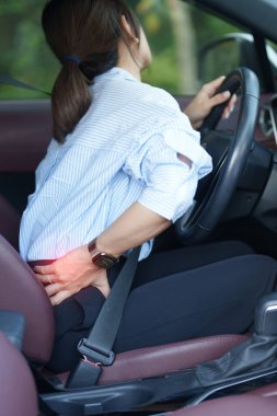 Uzun süre araba kullanırken sırtı burkulmuş bir kadın. Piriforis Sendromu, bel ağrısı ve omurga sıkışması nedeniyle sırt ağrısı çekiyor. Ergonomik ve tıbbi konsept