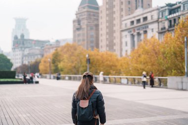 Çin, Şangay 'ı ziyaret eden bir kadın gezgin. Sonbahar sezonunda Şangay 'ın Bund of Shanghai manzaralı mutlu bayan turistler. Şehir simgesi ve turizm turizmi için popüler. Seyahat ve Tatil 