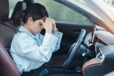 Araba kullanırken gergin ve sinirli bir kadın. Asyalı kız trafikte araba kullandıktan sonra yorgun ve yorgun düşüyor. Uykulu, esnetici ve sarhoş konsepti