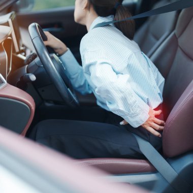 Uzun süre araba kullanırken sırtı burkulmuş bir kadın. Piriforis Sendromu, bel ağrısı ve omurga sıkışması nedeniyle sırt ağrısı çekiyor. Ergonomik ve tıbbi konsept