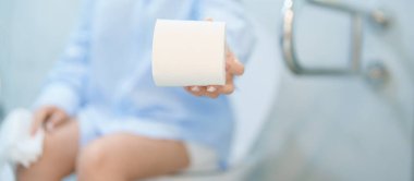 Tuvalet deliğinde otururken elinde tuvalet kağıdı tutan kadın. Sindirim, kabızlık, gıda zehirlenmesi, enfeksiyon, abdominal, mide ağrısı, sistit, sigorta, sağlık ve tıbbi yardım