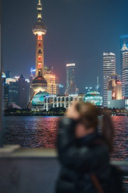 Çin, Şangay 'ı ziyaret eden bir kadın gezgin. Sırt çantalı bir bayan turist Şangay 'da Lujiazui' nin Şangay 'daki Bund of Shanghai manzarasını seyrediyor. tarihi eser ve turizm turizmi için popüler.