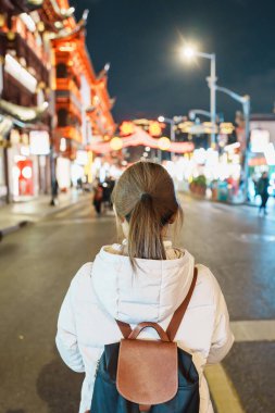 Çin, Şangay 'ı ziyaret eden bir kadın gezgin. Gece Yuyuan Eski Sokak pazarında mutlu bayan turist gezileri ve alışverişleri. Şehir simgesi ve turizm turizmi için popüler. Seyahat ve Tatil 