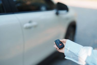 El ele tutuşan araba uzaktan kumandası, beyaz arabanın kapılarını kilitlemek ya da açmak için akıllı anahtar. Güvenlik, seyahat ve ulaşım kavramı