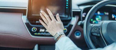Woman hand adjusting temperature the air flowing during driving car on the road, air conditioner cooling system inside the car. Adjust, temperature and transport concept