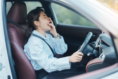 Kadın uzun süre araba kullanırken uykulu ve esnemiş hissediyor. Asyalı kız trafikte araba kullandıktan sonra yorgun ve yorgun düşüyor. Uyku, esneme ve güvenlik kavramı