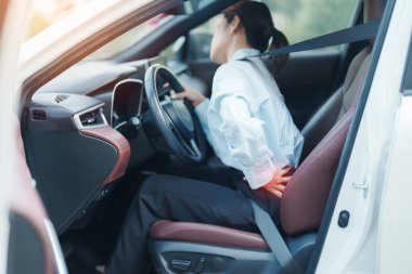 Uzun süre araba kullanırken sırtı burkulmuş bir kadın. Piriforis Sendromu, bel ağrısı ve omurga sıkışması nedeniyle sırt ağrısı çekiyor. Ergonomik ve tıbbi konsept