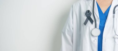 Melanoma ve cilt kanseri, aşı hasarı farkındalığı ayı ve huzur içinde yatma kavramları. Doktor elinde siyah kurdele tutuyor.