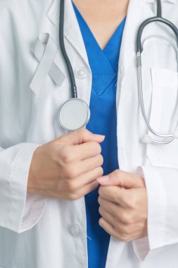 Beyin Kanseri Farkındalığı Mayıs ayında, gri renkli kurdeleli doktor, yaşam insanlarını desteklediği için. Sağlık ve Dünya Kanser Günü konsepti