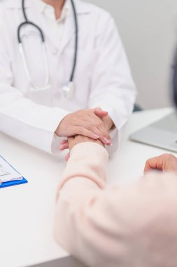 Doktor yaşlı kadın hastayla el ele tutuşuyor. Tıbbi konsültasyon sırasında empati ve destek gösteriyor. Güven, yaşlılar ve yaşlılar için sağlık, akıl sağlığı, danışmanlık ve duygusal danışmanlık 