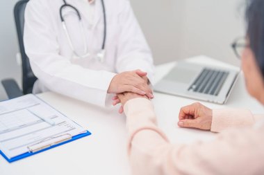 Doktor yaşlı kadın hastayla el ele tutuşuyor. Tıbbi konsültasyon sırasında empati ve destek gösteriyor. Güven, yaşlılar ve yaşlılar için sağlık, akıl sağlığı, danışmanlık ve duygusal danışmanlık 