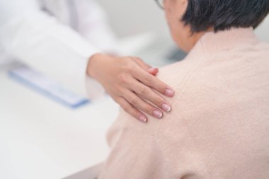 Doktor yaşlı kadın hastayla el ele tutuşuyor. Tıbbi konsültasyon sırasında empati ve destek gösteriyor. Güven, yaşlılar ve yaşlılar için sağlık, akıl sağlığı, danışmanlık ve duygusal danışmanlık 