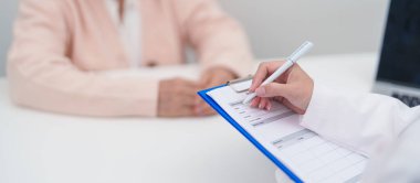 Hastanedeki doktora danışmanlık yapan kıdemli bir kadın. Yaşlı hasta konuşuyor ve hastalıkları paylaşıyor. Doktor dinler, soru sorar ve not alır. Tıbbi danışmanlık ve yaşlılık sağlığı konsepti 