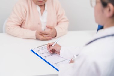 Hastanedeki doktora danışmanlık yapan kıdemli bir kadın. Yaşlı hasta konuşuyor ve hastalıkları paylaşıyor. Doktor dinler, soru sorar ve not alır. Tıbbi danışmanlık ve yaşlılık sağlığı konsepti 