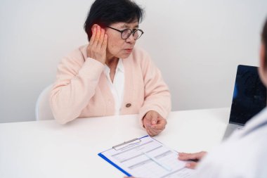 Kulak ağrısı olan yaşlı kadın hasta ve kulak hastalıkları için doktora danışmak. Kıdemli Sağlık Teşhisi. Atresia, Otitis Media, Pertorated Eardrum, Meniere Sendromu, otolaryngologist, İşitme Kaybı