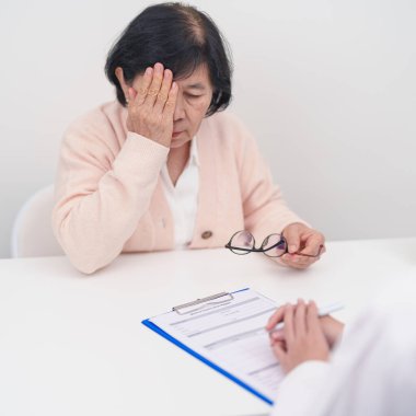Yaşlı kadın hasta göz ağrısı çekiyor ve göz hastalıkları doktoruna danışıyor. Kıdemli Tıbbi Teşhis. Katarakt, glikoma, Yaşla İlgili Maküler Dejenerasyon, Diyabetik Retinopati, Vitreöz ve Sağlık 