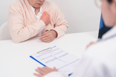Yaşlı hasta kadın göğüs ağrısı çekiyor ve danışman doktor. Kalp hastalığı, anjin hastalığı ve semptom kalp krizi hastalığı kardiyovasküler, atheroskleroz, hipertansif, dünya kalp günü ve sağlık
