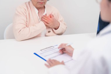 Yaşlı hasta kadın göğüs ağrısı çekiyor ve danışman doktor. Kalp hastalığı, anjin hastalığı ve semptom kalp krizi hastalığı kardiyovasküler, atheroskleroz, hipertansif, dünya kalp günü ve sağlık