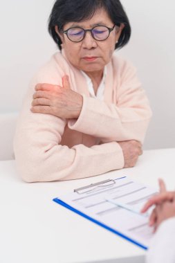 Omuz ve Boyun 'u olan yaşlı kadın ve hastanede danışman doktor. Miyofasyal ağrı sendromu, fibromiyalji, romatizma, skapüler ağrı, boyun omurgası. ergonomik kavram