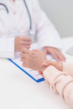 Yaşlı Hasta Kadın bilek ağrısı ve danışman doktor. Karpal Tünel Sendromu, De Quervain 's tenosilovitis, romatizma, artrit, gut, Parkinson hastalığı ve ergonomik sağlık sigortası yüzünden kas ağrısı. 