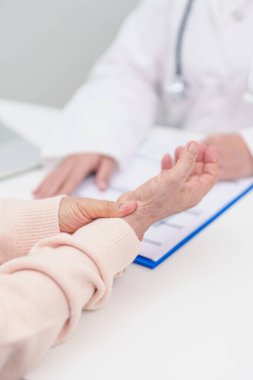 Yaşlı Hasta Kadın bilek ağrısı ve danışman doktor. Karpal Tünel Sendromu, De Quervain 's tenosilovitis, romatizma, artrit, gut, Parkinson hastalığı ve ergonomik sağlık sigortası yüzünden kas ağrısı. 