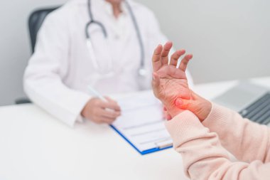Yaşlı Hasta Kadın bilek ağrısı ve danışman doktor. Karpal Tünel Sendromu, De Quervain 's tenosilovitis, romatizma, artrit, gut, Parkinson hastalığı ve ergonomik sağlık sigortası yüzünden kas ağrısı. 