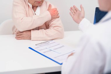 Omuz ve Boyun 'u olan yaşlı kadın ve hastanede danışman doktor. Miyofasyal ağrı sendromu, fibromiyalji, romatizma, skapüler ağrı, boyun omurgası. ergonomik kavram
