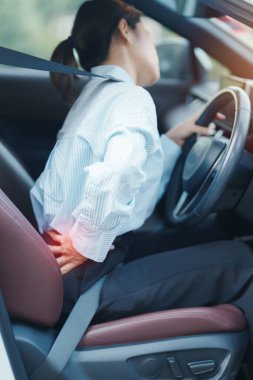 Uzun süre araba kullanırken sırtı burkulmuş bir kadın. Piriforis Sendromu, bel ağrısı ve omurga sıkışması nedeniyle sırt ağrısı çekiyor. Ergonomik ve tıbbi konsept