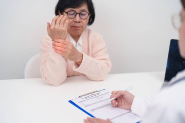 Yaşlı Hasta Kadın bilek ağrısı ve danışman doktor. Karpal Tünel Sendromu, De Quervain 's tenosilovitis, romatizma, artrit, gut, Parkinson hastalığı ve ergonomik sağlık sigortası yüzünden kas ağrısı. 