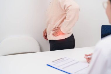 Yaşlı bir kadın sırt ağrısı çekiyor ve hastanede danışmanlık yapıyor. Piriforis Sendromu, bel ağrısı ve omurga baskısı nedeniyle kas ağrısı olan yaşlı bir kadın. Ofis sendromu ve tıbbi 