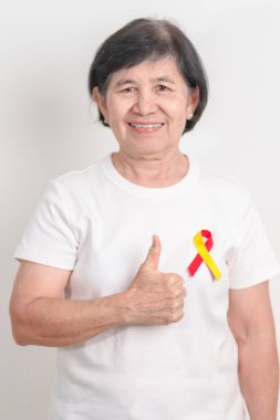 Dünya Hepatit Günü farkındalık ayı, 28 Temmuz. Kırmızı ve sarı kurdeleli yaşlı kadın. Karaciğer kanseri, sarılık, siroz, başarısızlık, büyüme, Hepatik Ensefalopati ve Sağlık Konsepti