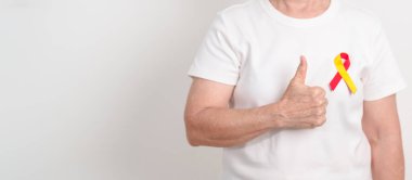 Dünya Hepatit Günü farkındalık ayı, 28 Temmuz. Kırmızı ve sarı kurdeleli yaşlı kadın. Karaciğer kanseri, sarılık, siroz, başarısızlık, büyüme, Hepatik Ensefalopati ve Sağlık Konsepti