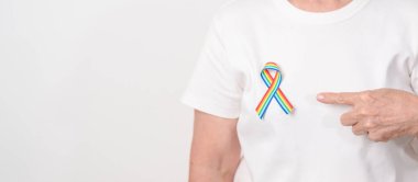 Haziran Gurur Ayı, Nisan Otizm Bilinci, Kanser Farkındalığı, Şubat Dünya Kanser Günü, Ekim Dünya Bakımevi ve Palyatif Bakım Günü konsepti için LGBTQ Gökkuşağı kurdelesine sahip yaşlılar