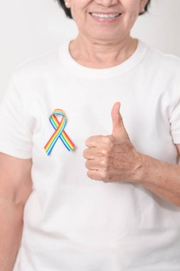 Haziran Gurur Ayı, Nisan Otizm Bilinci, Kanser Farkındalığı, Şubat Dünya Kanser Günü, Ekim Dünya Bakımevi ve Palyatif Bakım Günü konsepti için LGBTQ Gökkuşağı kurdelesine sahip yaşlılar