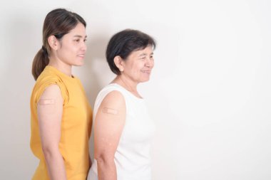 Aşı olduktan sonra bandajlı yetişkin ve yaşlı kadın. Grip aşısı, HPV, Zoster, IPD, DTP, Dang, Ensefalit, Kuduz, Pnömokok Hepatit B ve Covid aşısı