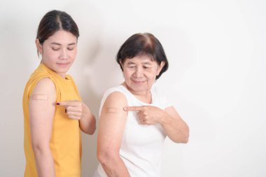 Aşı olduktan sonra bandajlı yetişkin ve yaşlı kadın. Grip aşısı, HPV, Zoster, IPD, DTP, Dang, Ensefalit, Kuduz, Pnömokok Hepatit B ve Covid aşısı