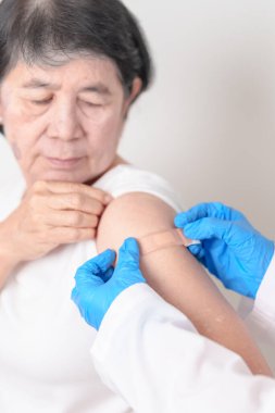 Elderly Woman with bandage after received vaccine. Vaccination and Immunization for Influenza, Herpes Zoster, Tetanus, Covid 19 booster, Dengue, Encephalitis, Rabies, Pneumococcal, IPD, RSV Vaccines 