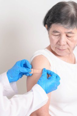 Elderly Woman with bandage after received vaccine. Vaccination and Immunization for Influenza, Herpes Zoster, Tetanus, Covid 19 booster, Dengue, Encephalitis, Rabies, Pneumococcal, IPD, RSV Vaccines 