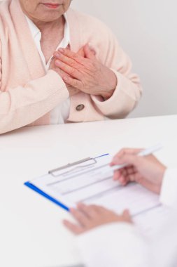 Yaşlı hasta kadın göğüs ağrısı çekiyor ve danışman doktor. Kalp hastalığı, anjin hastalığı ve semptom kalp krizi hastalığı kardiyovasküler, atheroskleroz, hipertansif, dünya kalp günü ve sağlık