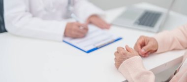 Hastanedeki doktora danışmanlık yapan kıdemli bir kadın. Yaşlı hasta konuşuyor ve hastalıkları paylaşıyor. Doktor dinler, soru sorar ve not alır. Tıbbi danışmanlık ve yaşlılık sağlığı konsepti 