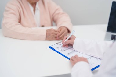 Hastanedeki doktora danışmanlık yapan kıdemli bir kadın. Yaşlı hasta konuşuyor ve hastalıkları paylaşıyor. Doktor dinler, soru sorar ve not alır. Tıbbi danışmanlık ve yaşlılık sağlığı konsepti 