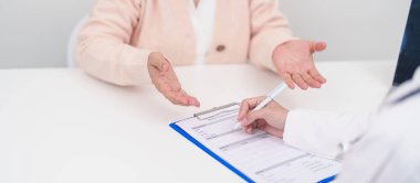 Hastanedeki doktora danışmanlık yapan kıdemli bir kadın. Yaşlı hasta konuşuyor ve hastalıkları paylaşıyor. Doktor dinler, soru sorar ve not alır. Tıbbi danışmanlık ve yaşlılık sağlığı konsepti 